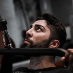 Muscular man working out with determination on gym equipment.